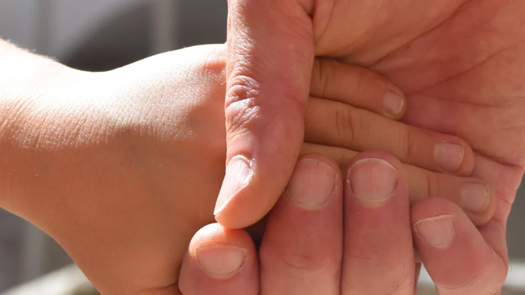 Immagine di una mando di adulto che stringe quella di un bambino